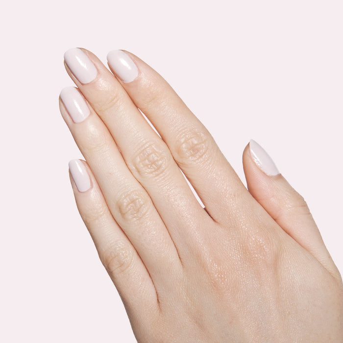 Hand with neatly manicured nails painted in soft neutral lavender grey The Usual polish for at home mani