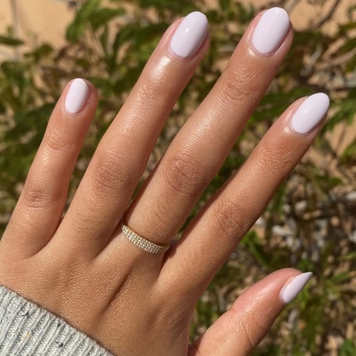 Hand with almond-shaped nails painted in glossy The Usual polish wearing delicate ring outdoors in sunlight