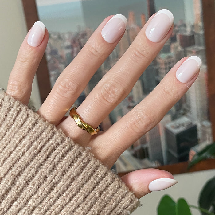 Classic French | Short | Round - Tab Press-On nails with natural base and white tips shown on hand wearing gold ring indoors