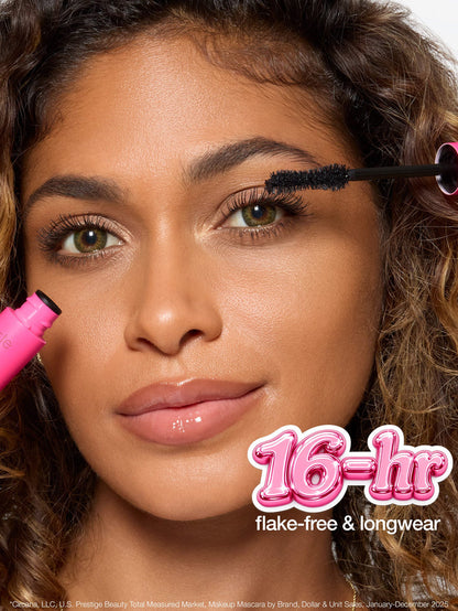 Mascara wand features twisted double fiber bristles for maximum pigment. Accompanying text highlights confidence booster brush, hourglass shape hugs lashline, and details for optimal makeup application. Background is plain.