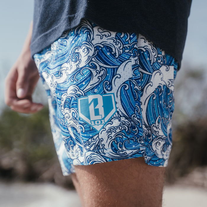 Youth model wearing blue youth shorts with “Wave” design