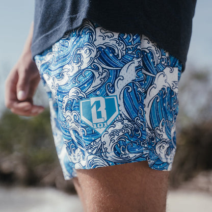 Youth model wearing blue youth shorts with “Wave” design
