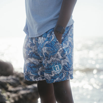 Youth model wearing blue youth shorts with “Wave” design