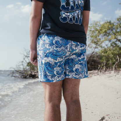 Youth model wearing blue youth shorts with “Wave” design