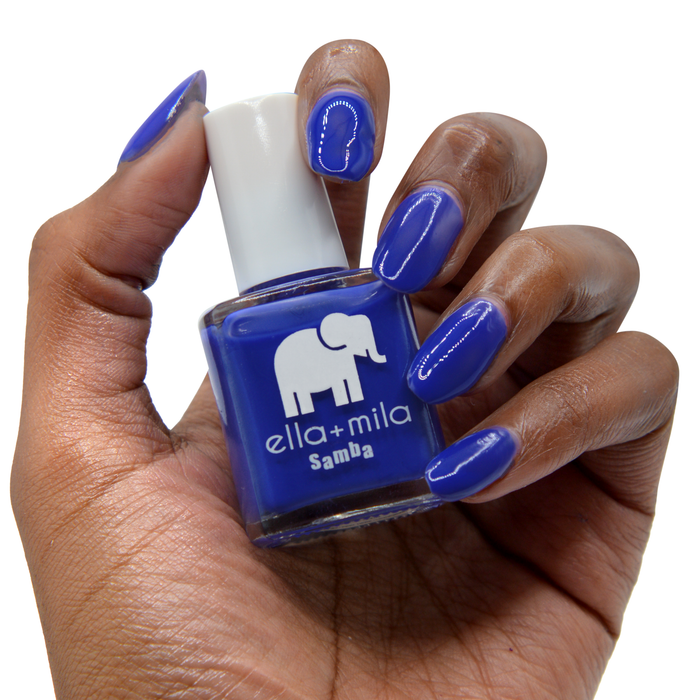 When the Sun Goes Down cobalt blue nail polish on a deep skin tone, hand holding the bottle