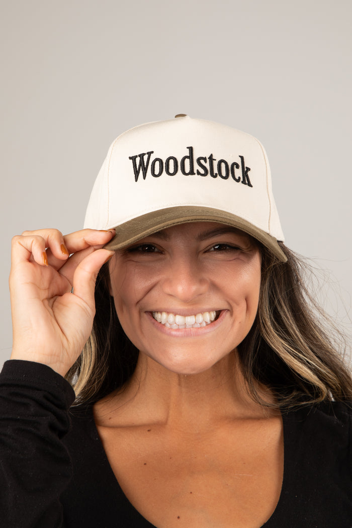 Person wearing a white cap with 'Woodstock' text on a plain background