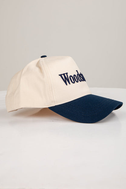 Beige and navy cap with 'Wooden' branding on a light gray background