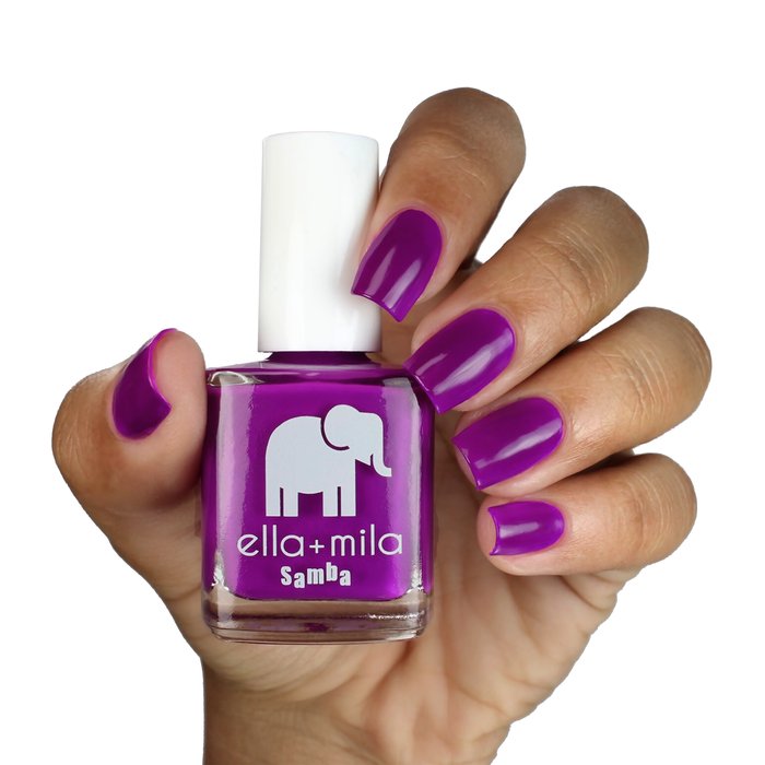 Yours at Dusk rosy purple nail polish on a medium skin tone, hand holding the bottle