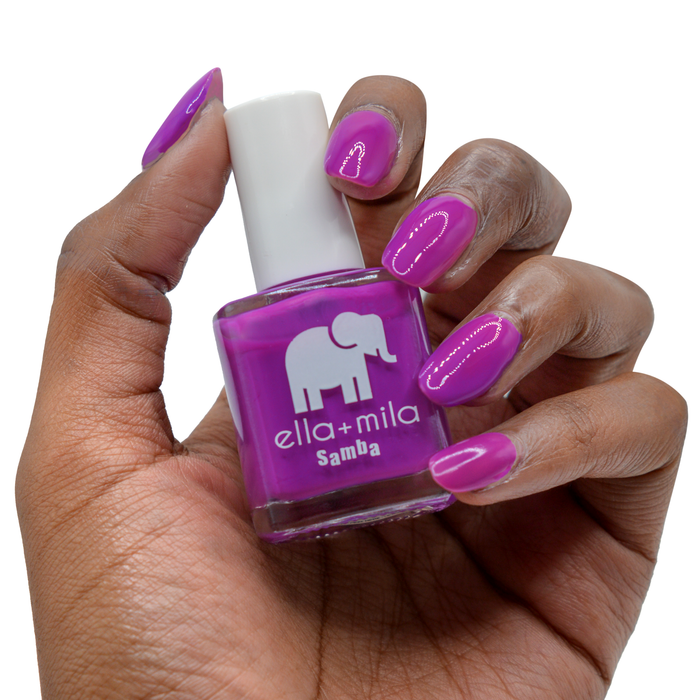 Yours at Dusk bright purple nail polish on a deep skin tone, hand holding the bottle